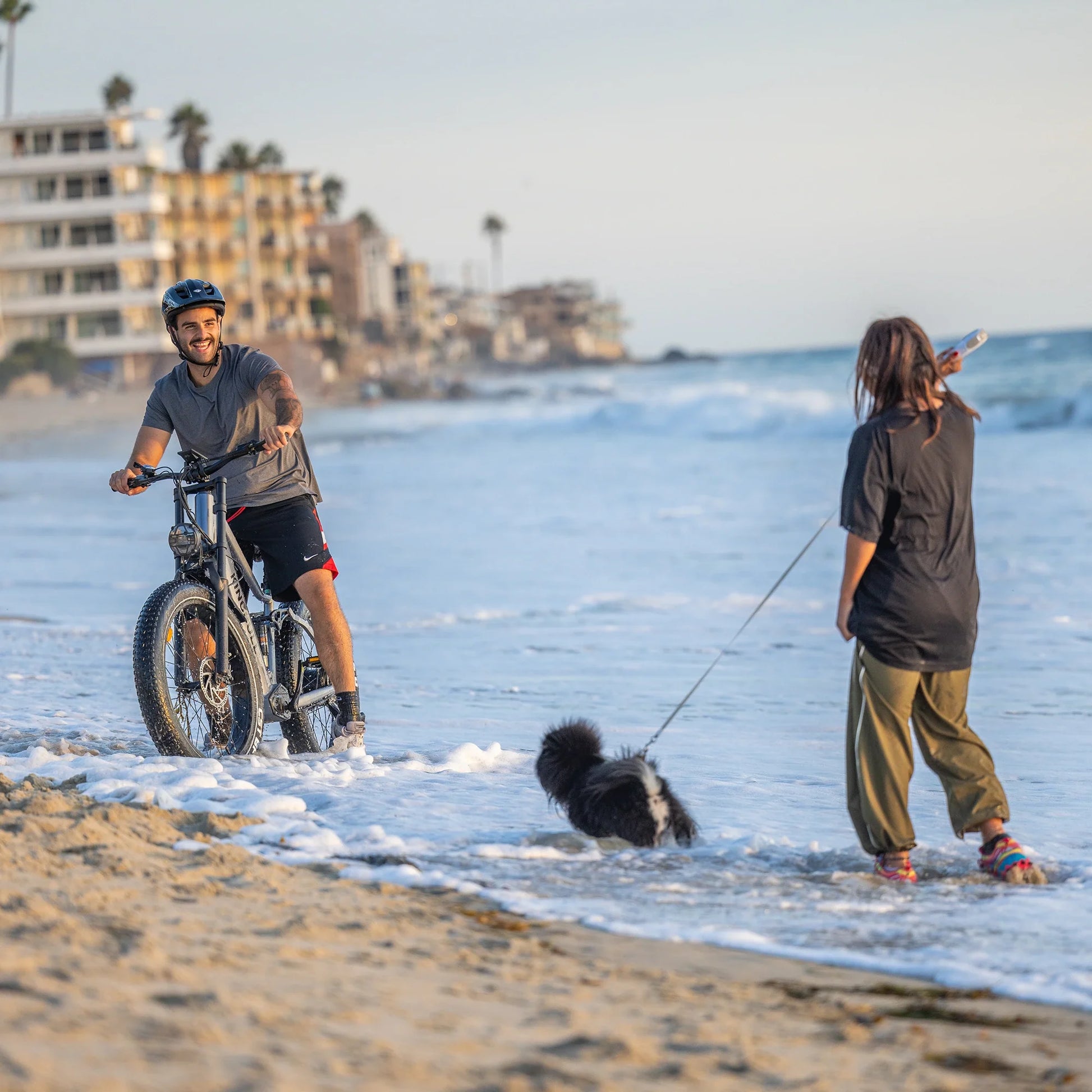 A man rides the Kingbull Rover Ebike and plays happily with a Women on the beach